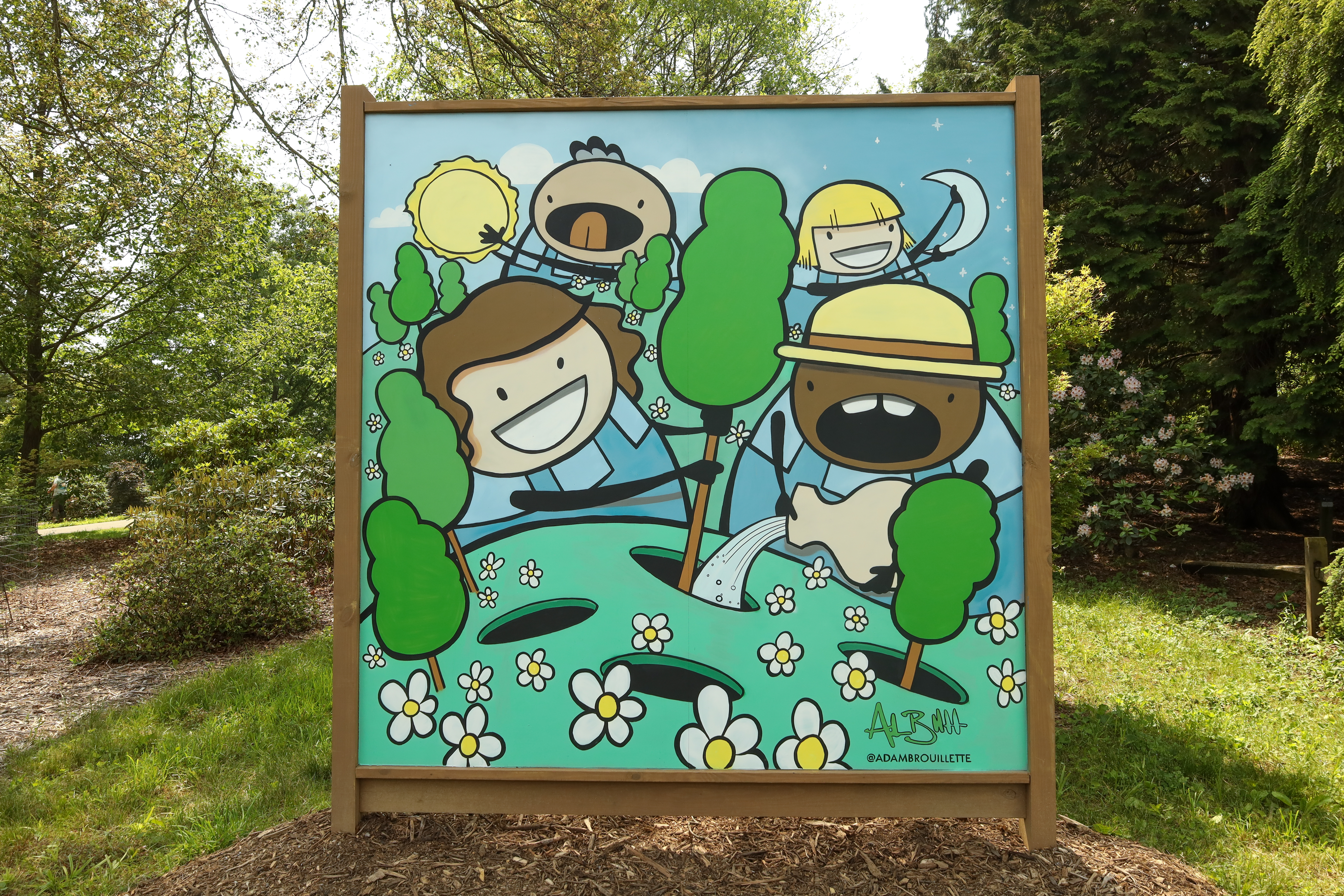 This mural uses blue, green, white and yellow. It has four figures on it that are makign silly expressions while planting trees, holding up the sun and the moon. It is placed on the Arboretum grounds surrounded by trees and grass. The frame is tan.