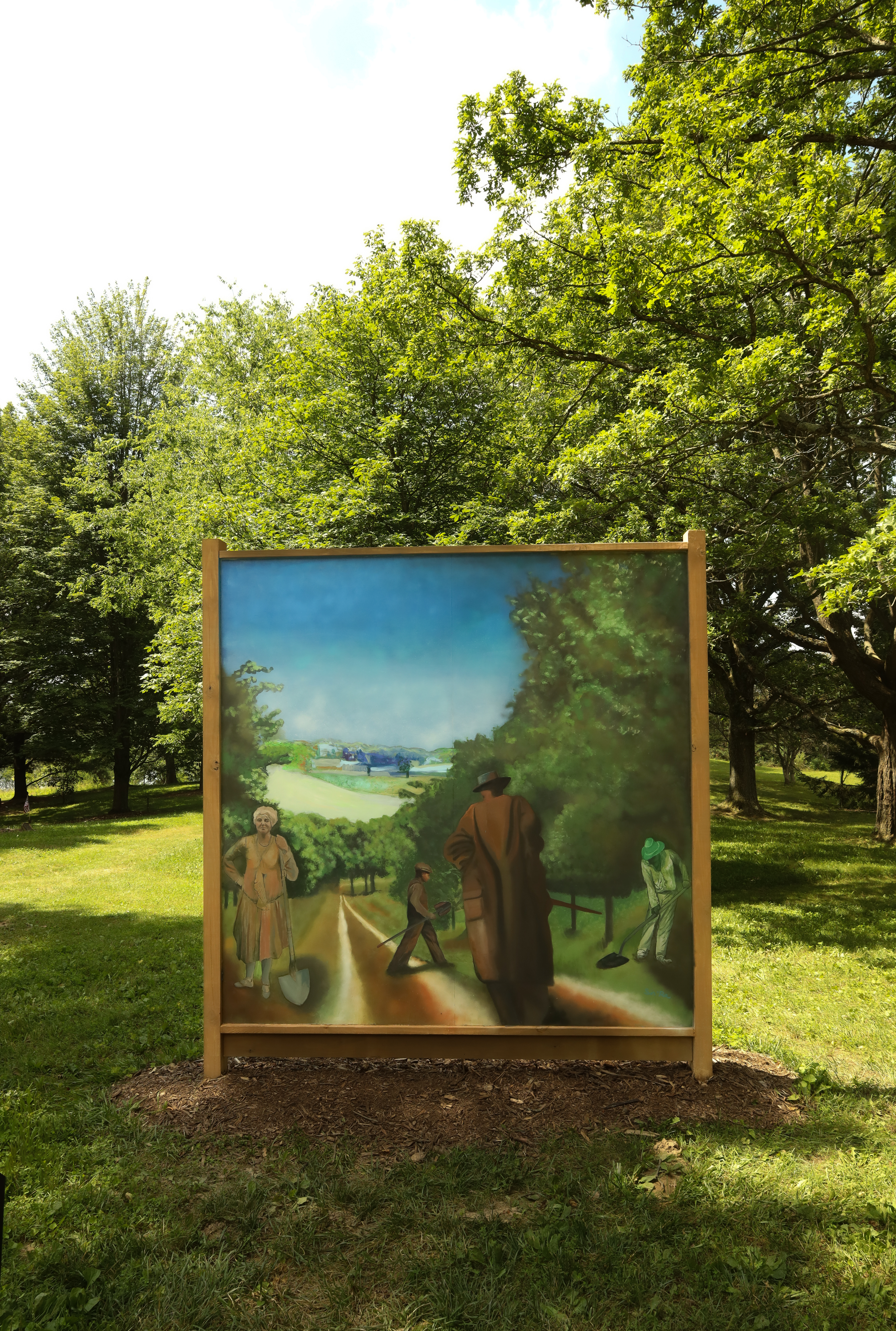 A mural sits on The Arboretum's grounds surrounded by green trees and grass. It has a tan frame. It features colors like green, brown and blue, and showcases Bertie Dawes looking in the painting as well as two other men.
