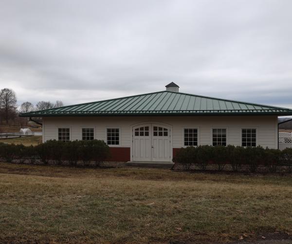 The Dawes Arboretum's Archive building sits with a green roof and white body right off of our South Auto Tour. A fountain can be seen in the distance from a pond. 